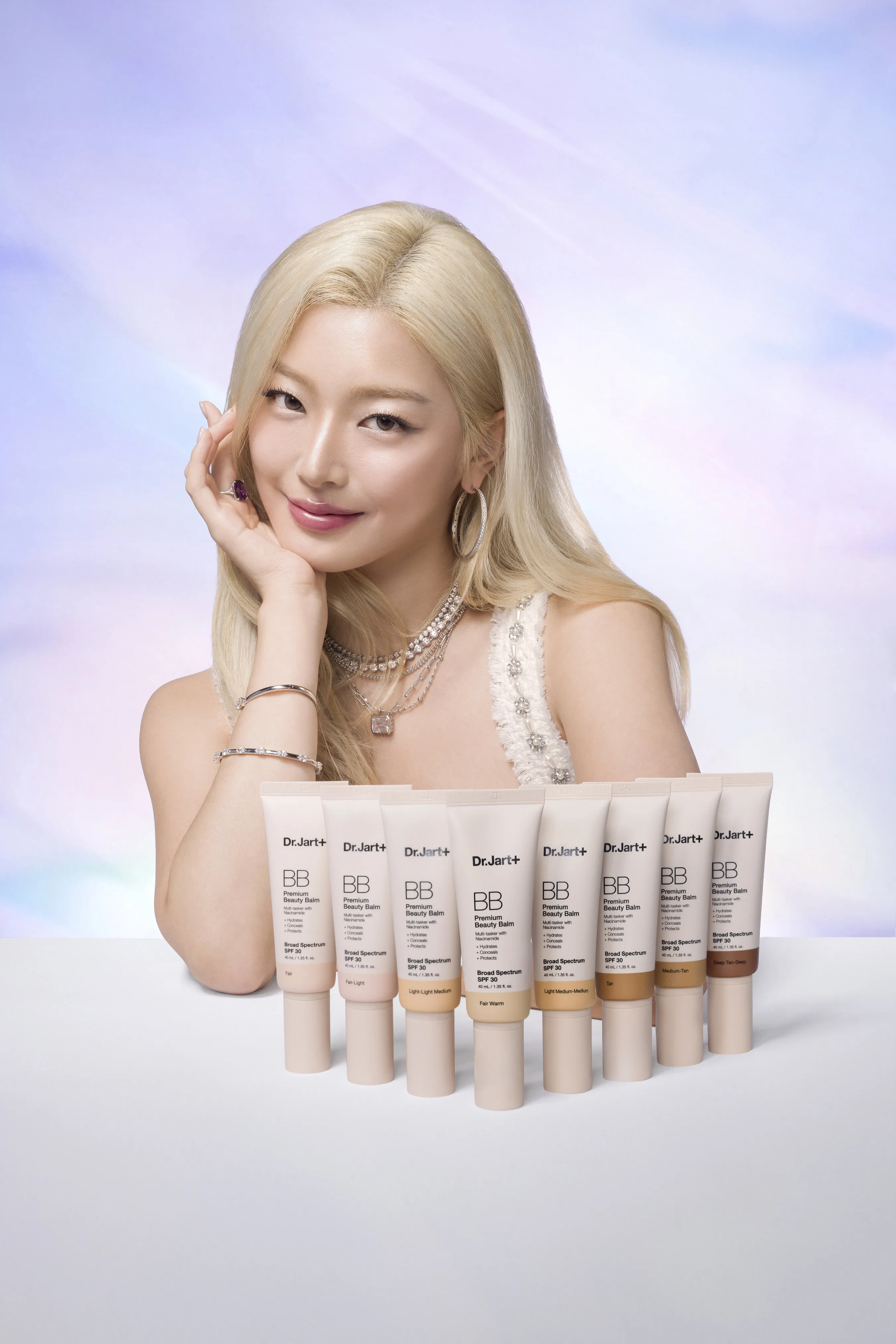 A blonde person poses beside eight tubes of Dr.Jart+ BB cream in assorted shades.