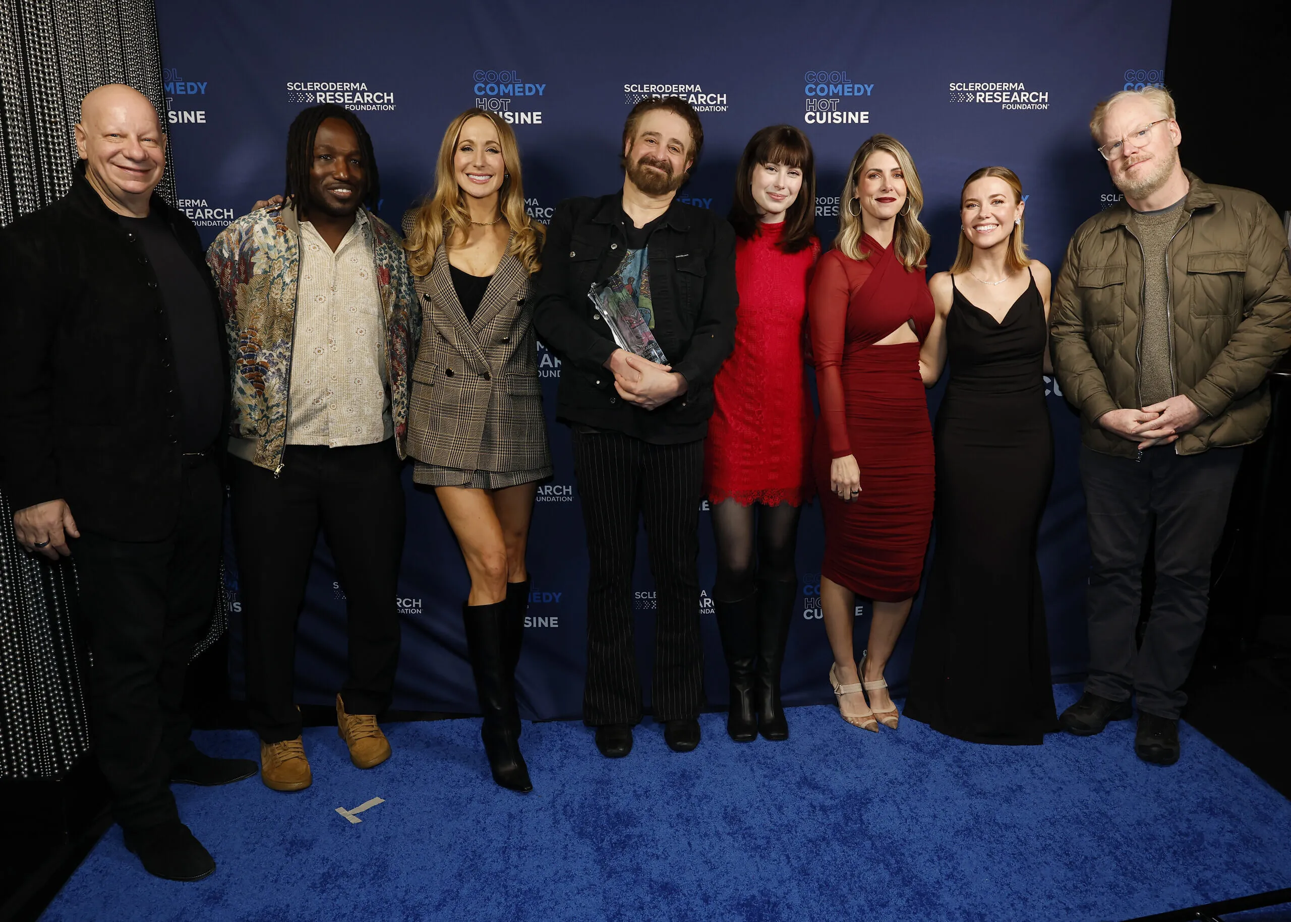 Eight people pose on a blue carpet before a Hot Cuisine and Scleroderma Research Foundation backdrop.