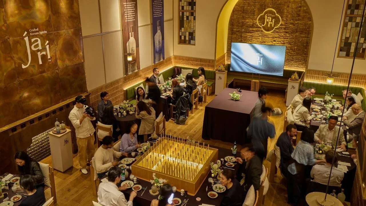 Guests dining at tables in a warmly lit Jari Korean Spirits event venue.