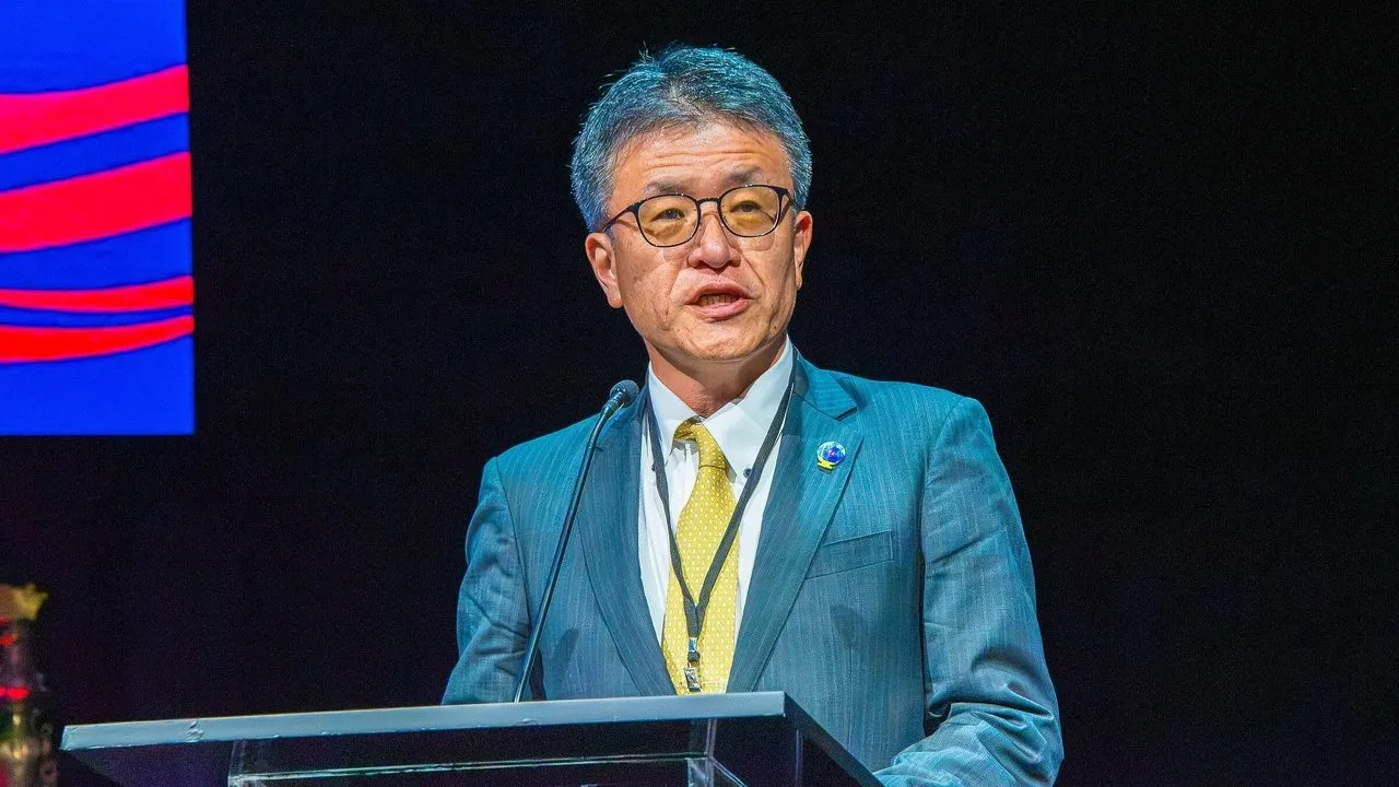 A man in a blue suit speaks at a podium.