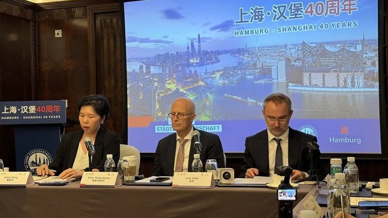 Three officials sit at a conference table before a Hamburg–Shanghai 40 years presentation screen.