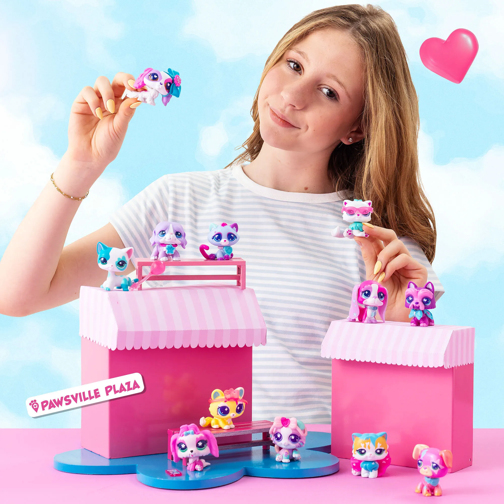 Girl arranging colorful Littlest Pet Shop figures on pink striped play stalls.