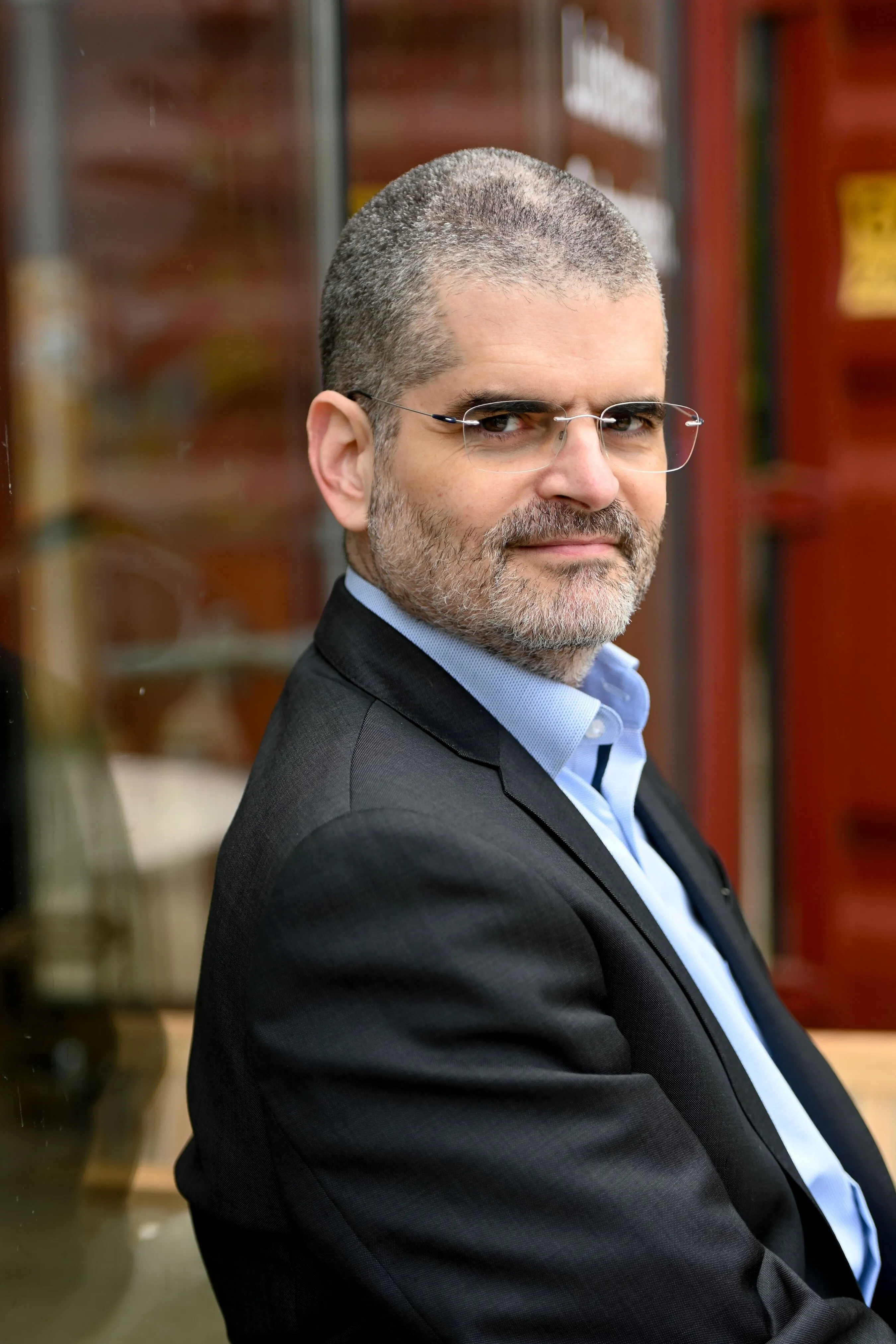 Bernardo Kastrup in glasses, a dark suit jacket and blue shirt, seated beside a window.