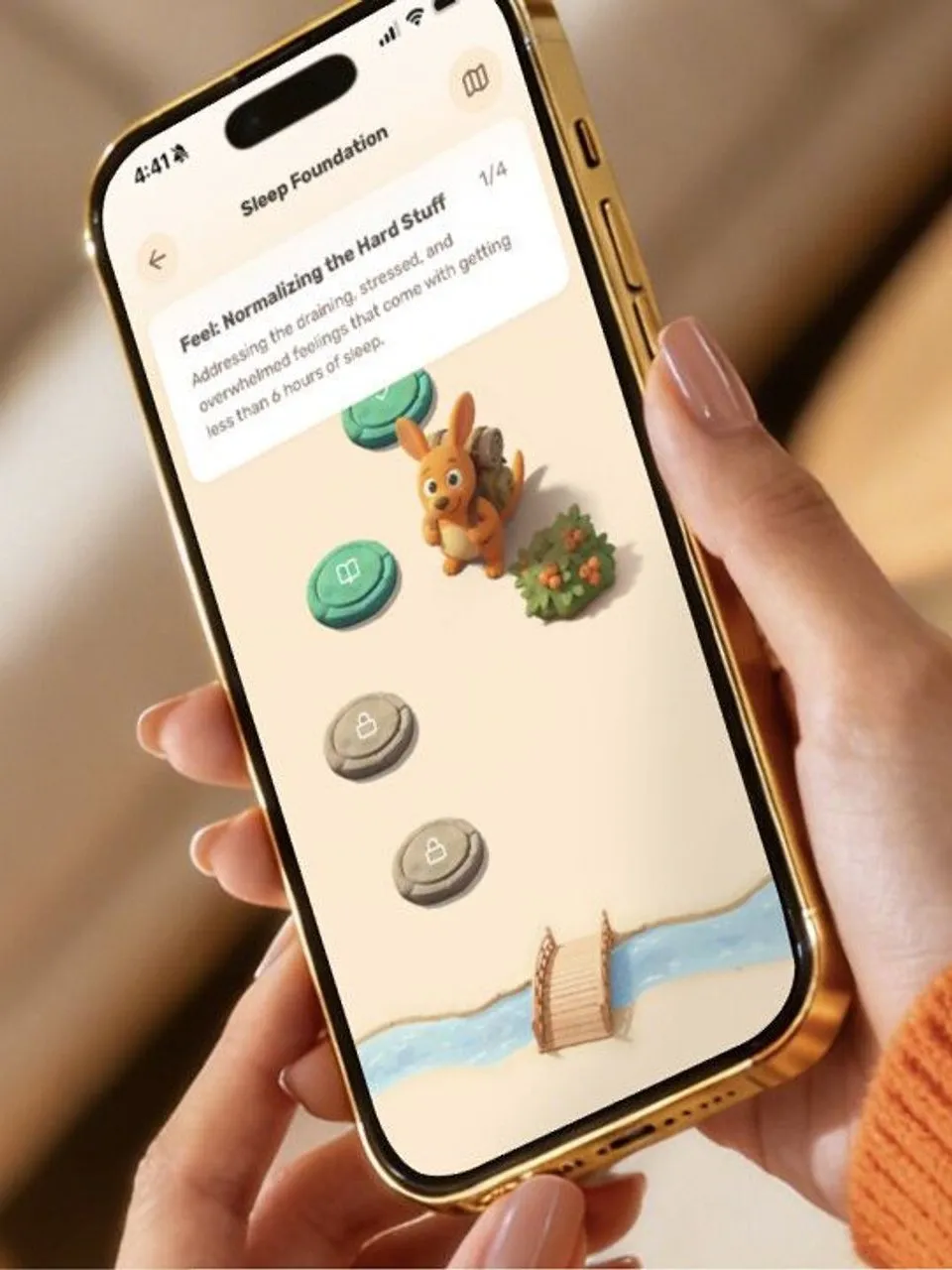 Hand holding a smartphone showing the Betteroo app, with a cartoon kangaroo on a progress path.