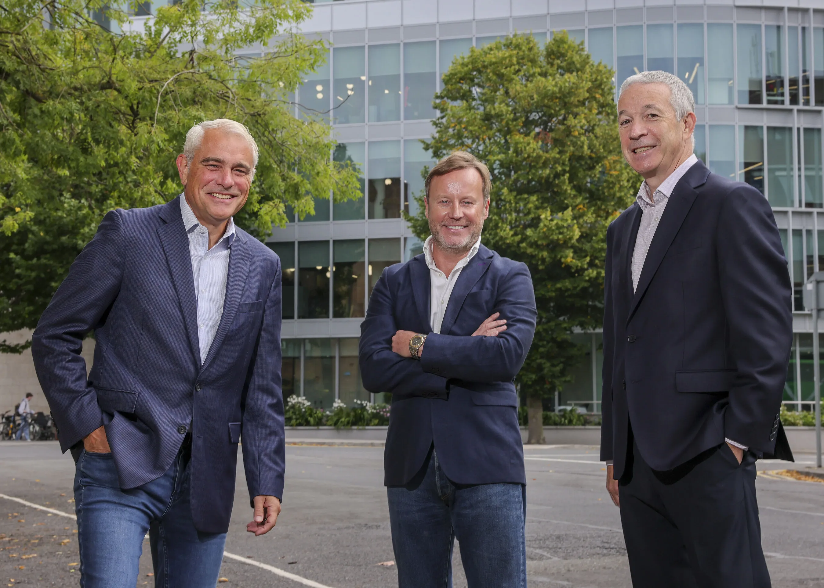 Three men in suits standing outside a modern office building.