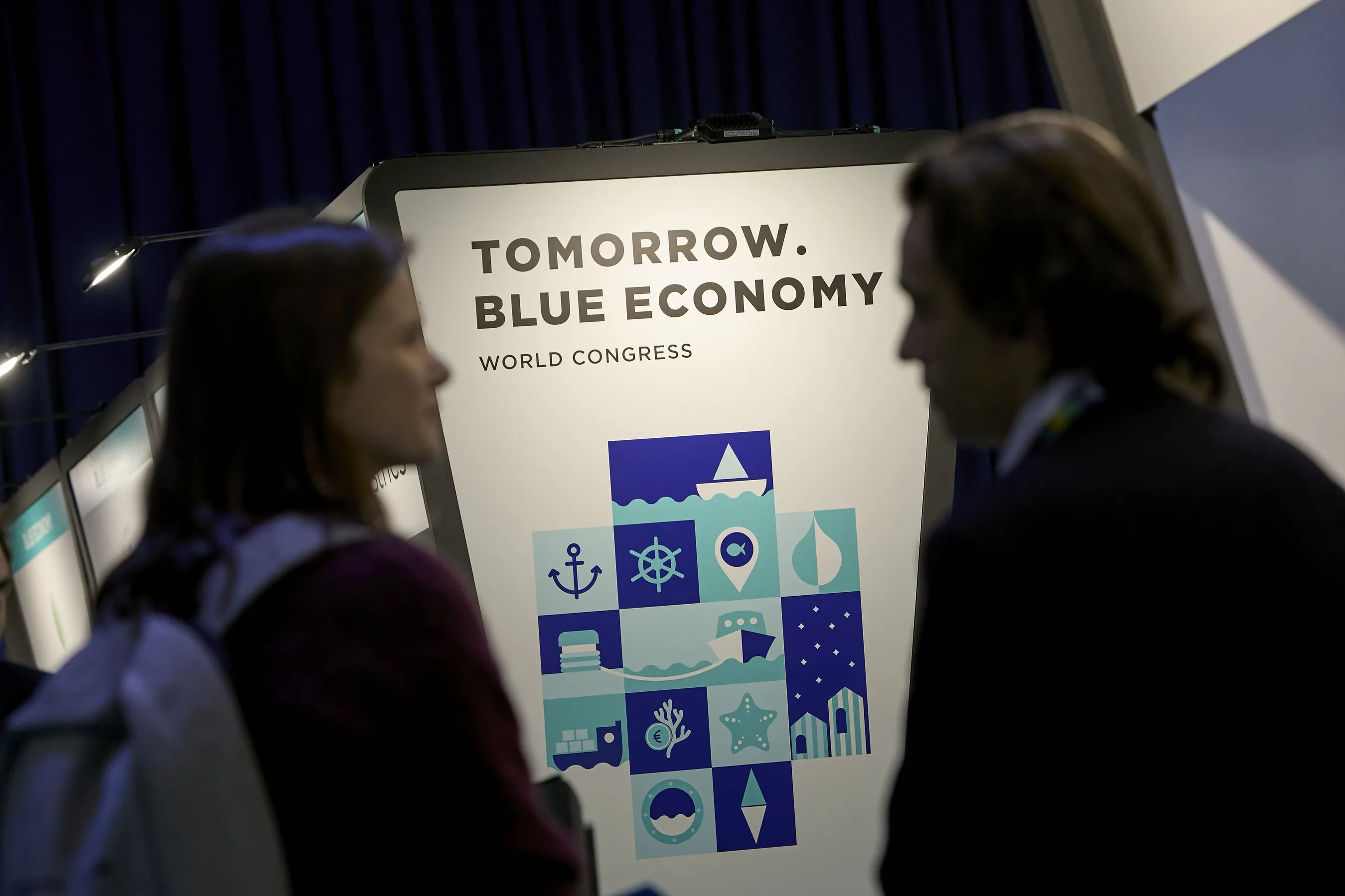 Two people stand beside a Tomorrow Blue Economy World Congress sign.