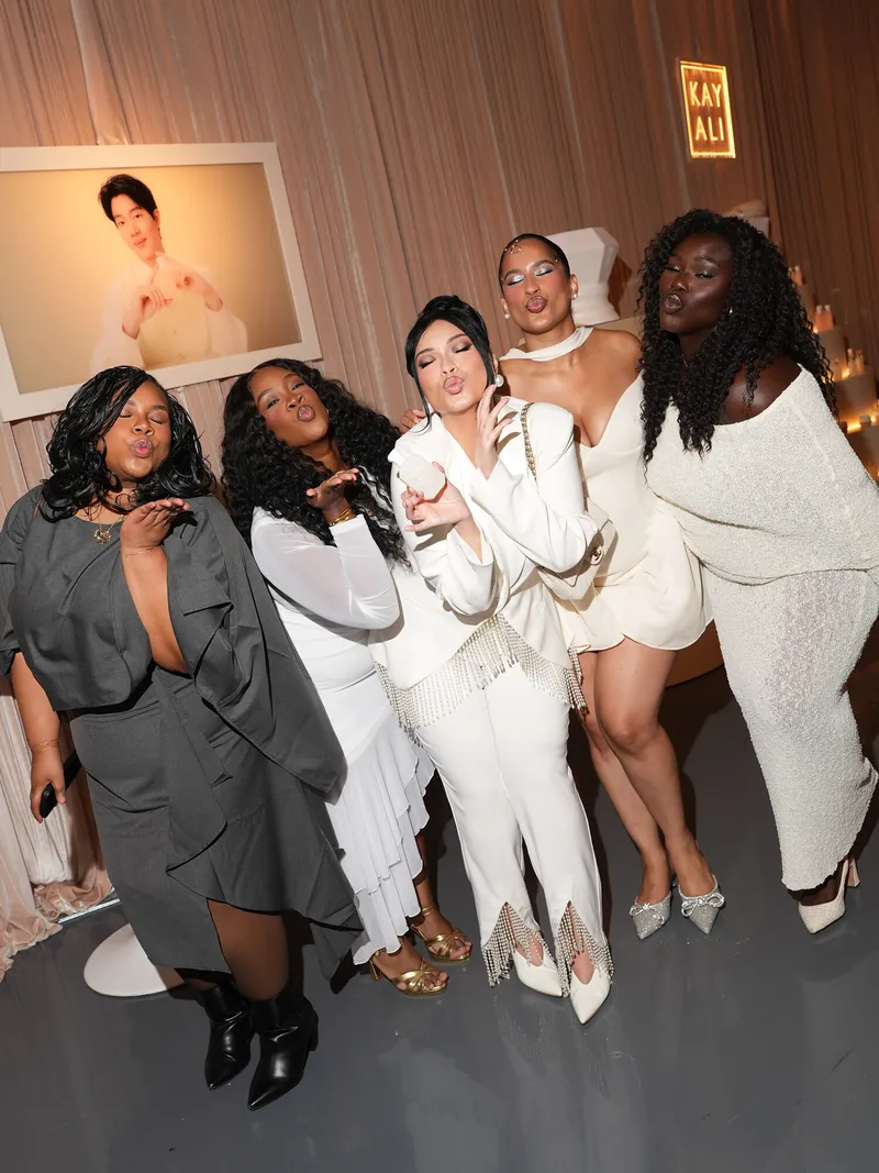 Five women pose in elegant outfits beneath a glowing KAYALI sign.
