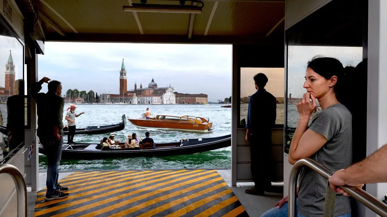 People aboard a Venice ferry watch gondolas and boats pass San Giorgio Maggiore.