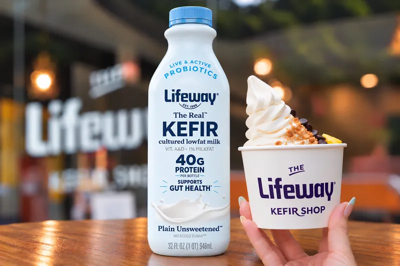 A Lifeway kefir bottle beside a cup of frozen kefir topped with fruit, nuts and chocolate chips.