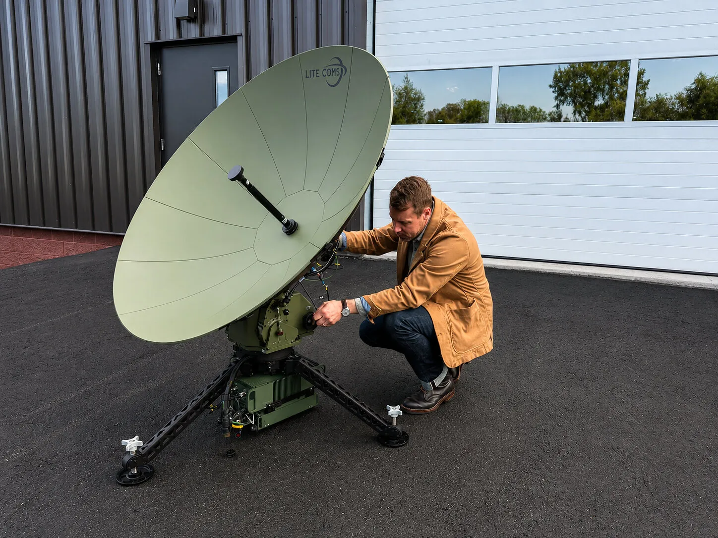 Rich Steixner adjusts a Lite Coms satellite dish outside a building.