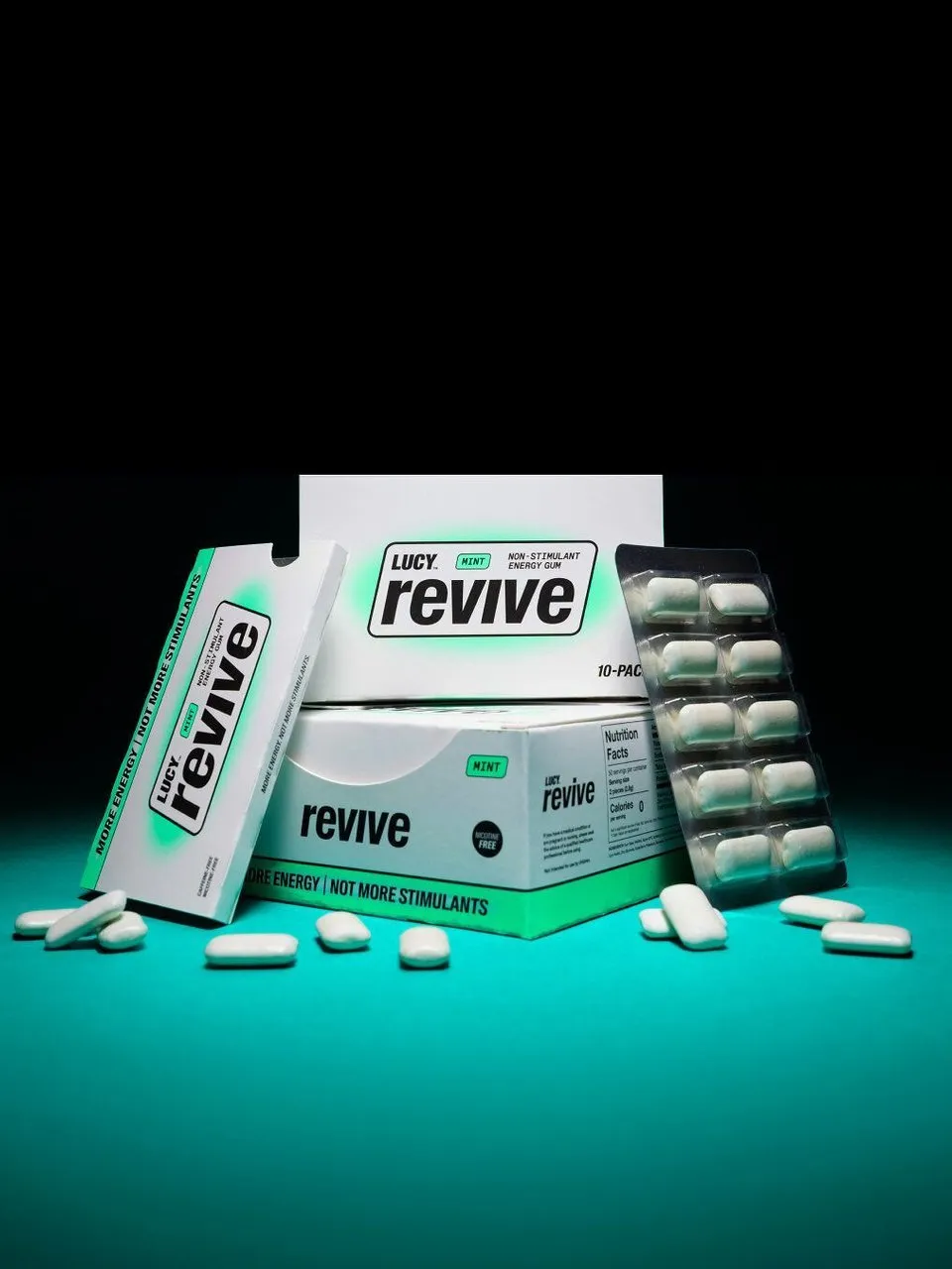 Lucy Revive mint energy gum boxes, blister pack and loose pieces on a turquoise surface