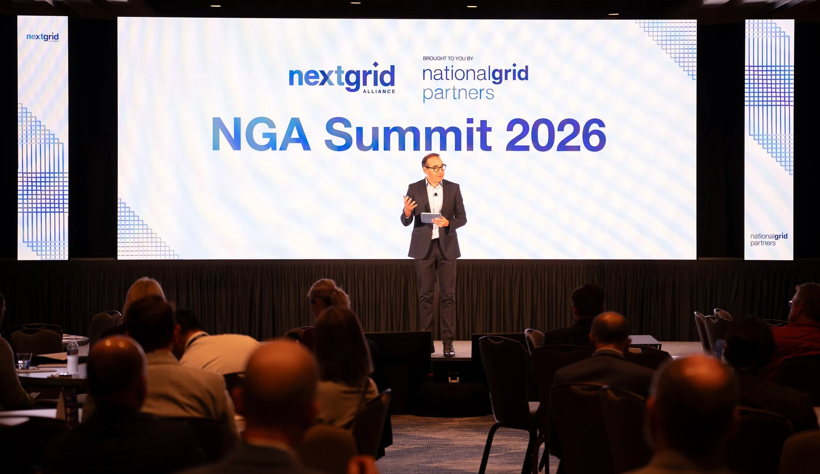 A speaker addresses an audience beneath a screen reading “NGA Summit 2026.”