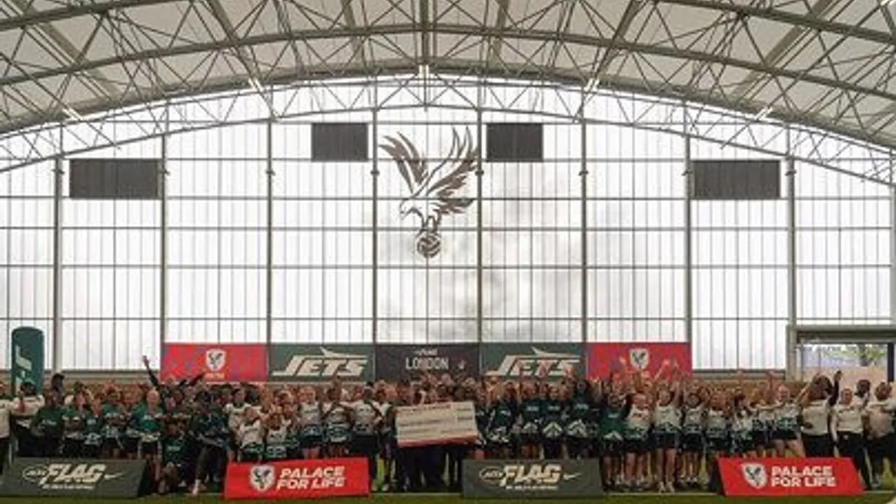A large group of people in sports uniforms posing inside an indoor training hall.