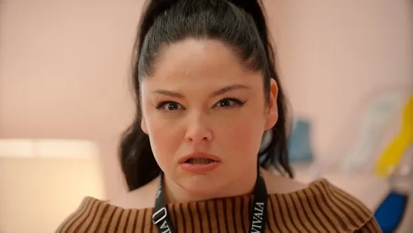 Woman wearing a brown ribbed sweater and VIVAIA lanyard making a surprised expression.