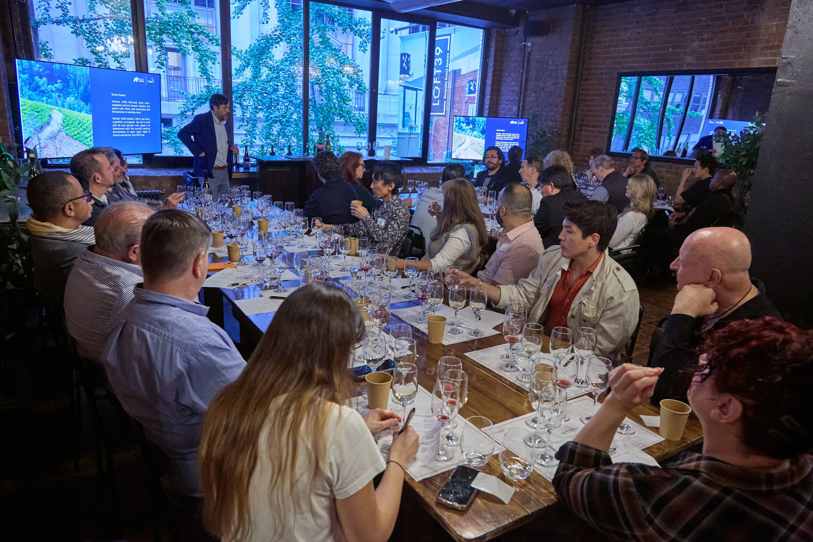 Guests seated around a long table tasting wine during a masterclass.