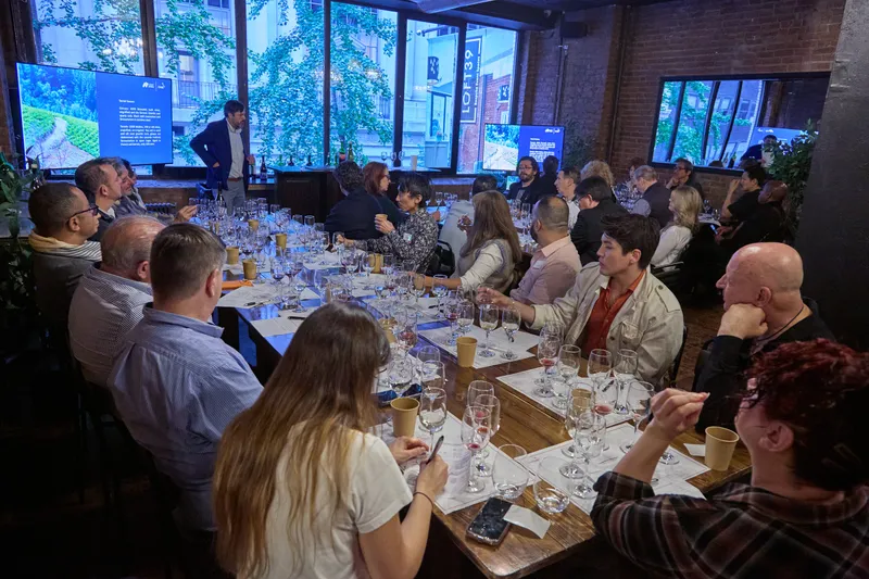 Guests seated around a long table tasting wine during a masterclass.