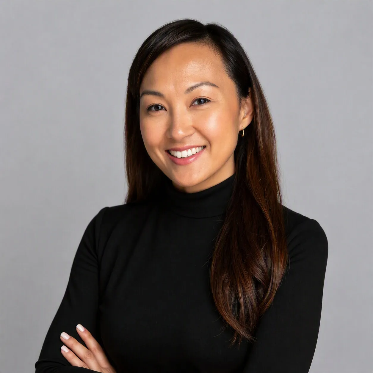 Angelica Munson smiling in a black turtleneck against a gray background.