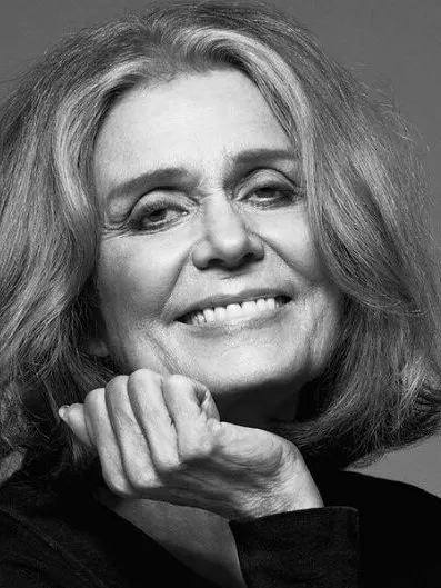 Black-and-white close-up portrait of a smiling woman resting her chin on her hand.